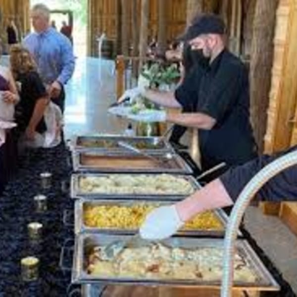 LX BBQ buffet line with a server dishing out food and guests waiting.